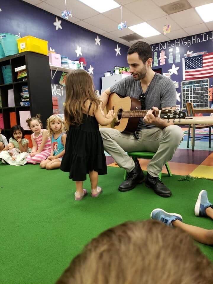 A man with a guitar and kid watching him