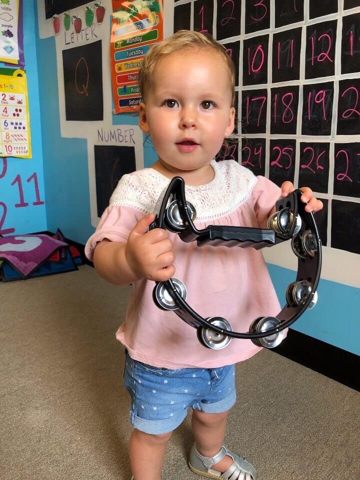 Child playing a tambourine at our music daycare in Owings Mills