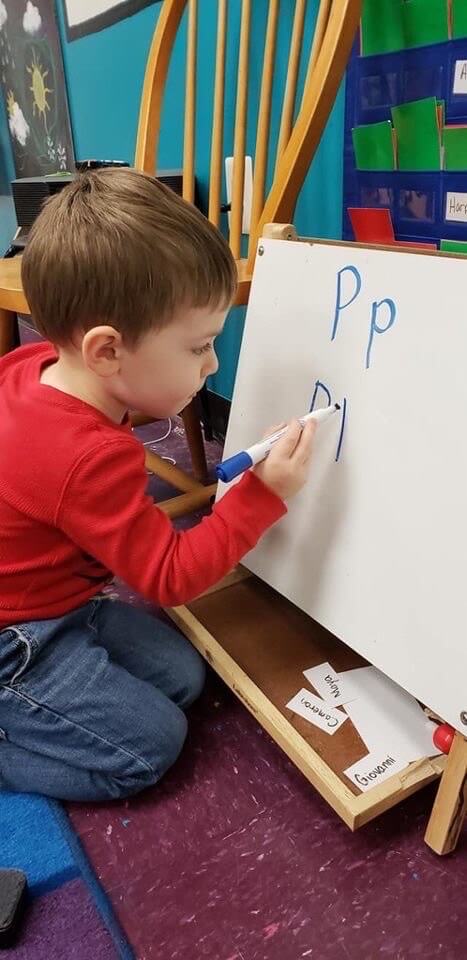 Kid write in the board the letter P