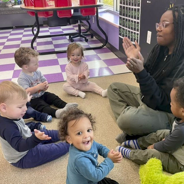 Children clapping with teacher in classroom.