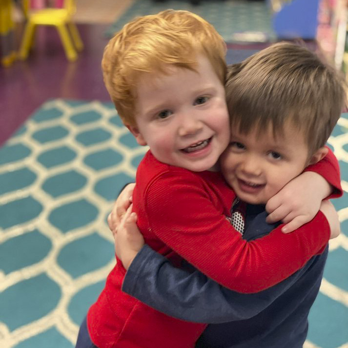 Two children hugging happily at our music daycare in Owings Mills