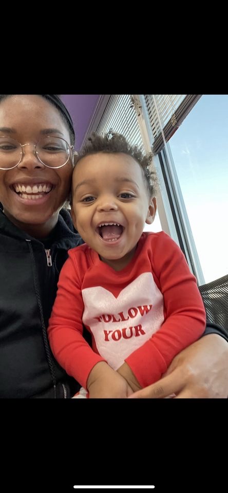 Smiling adult and child in red shirt indoors.