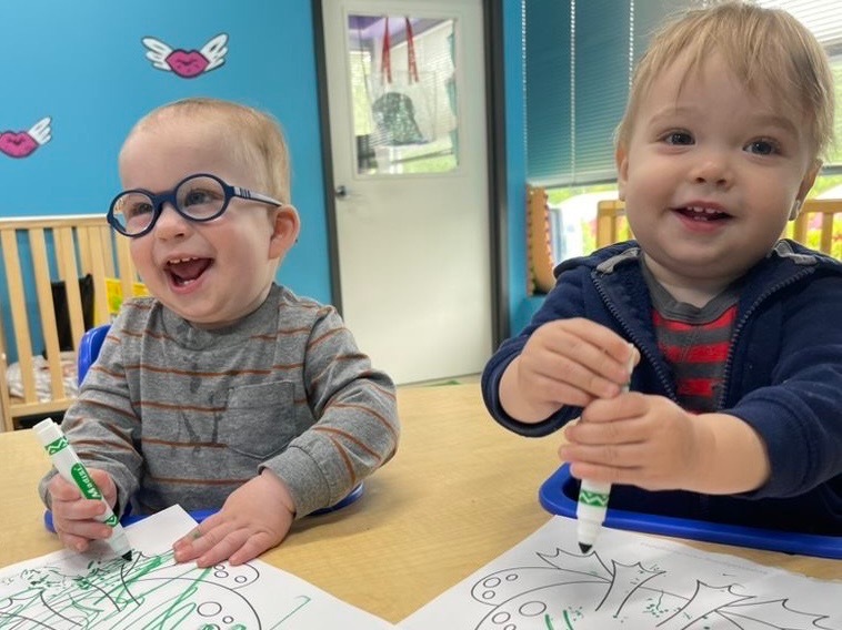 Happy toddlers coloring at a table at our music preschool in Owings Mills