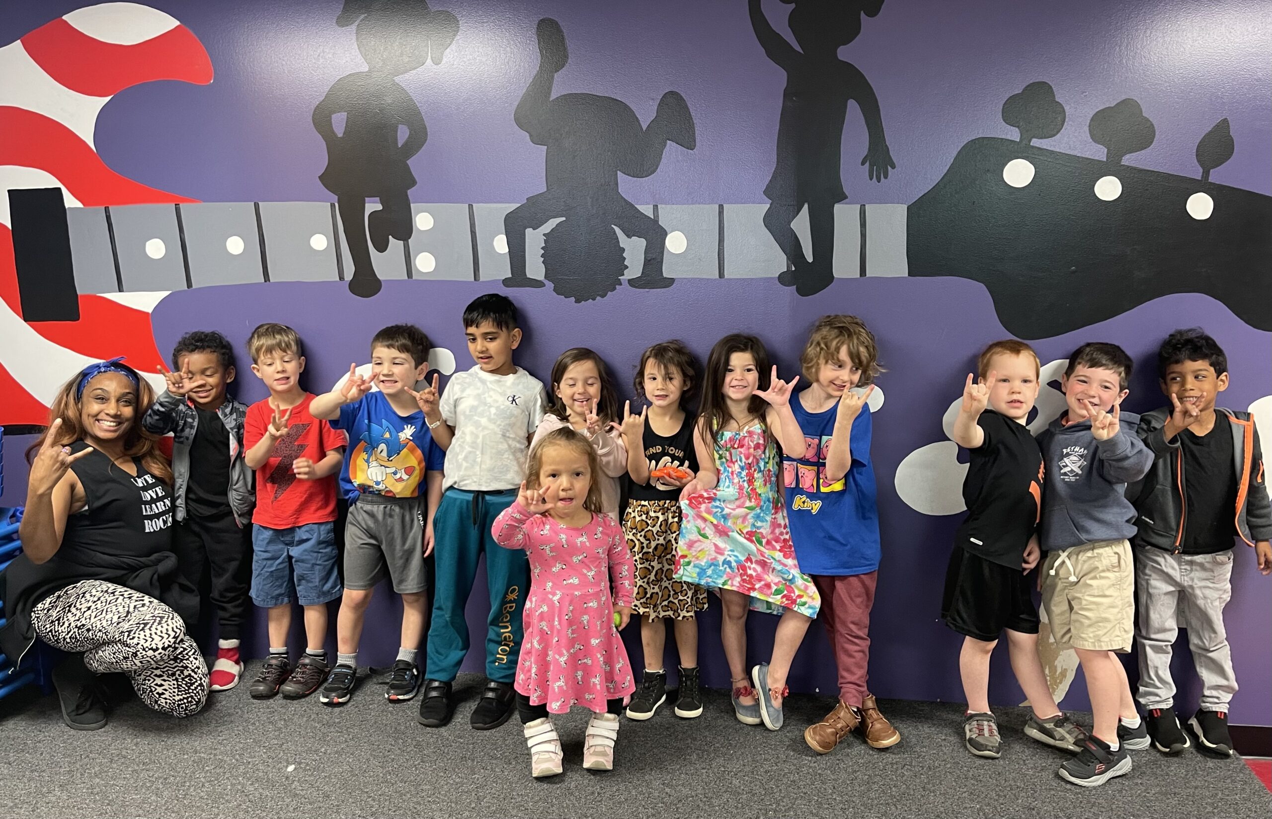 Group of children posing in front of musical mural.