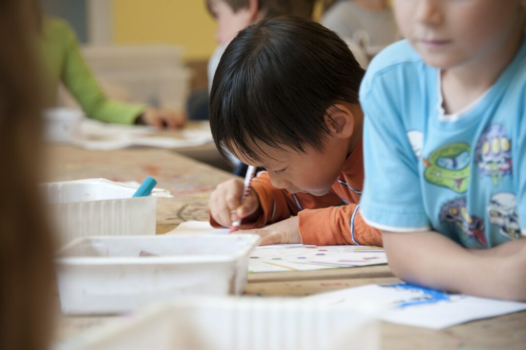 Children focusing on drawing in classroom setting.