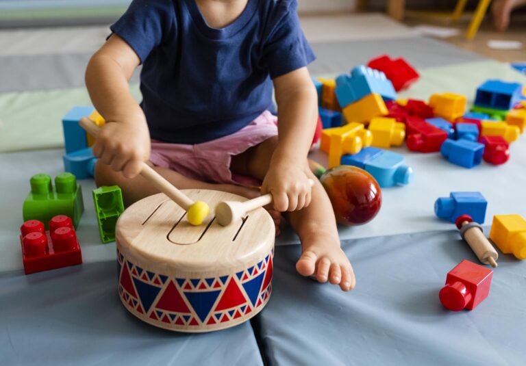 Child playing drum with wooden blocks around.